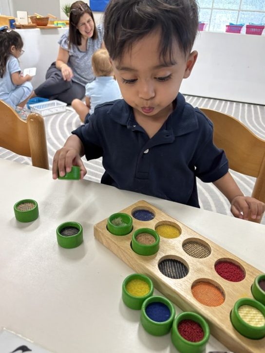A student fitting textured lids into a wooden matching tray at a table