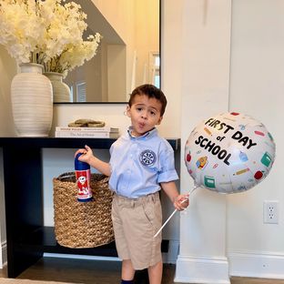 A student holding a first day of school balloon at home