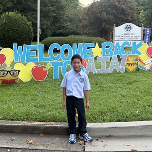 A student at the Welcome Back to AIA sign