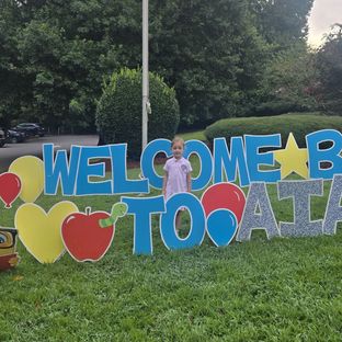 A student at the Welcome Back to AIA sign