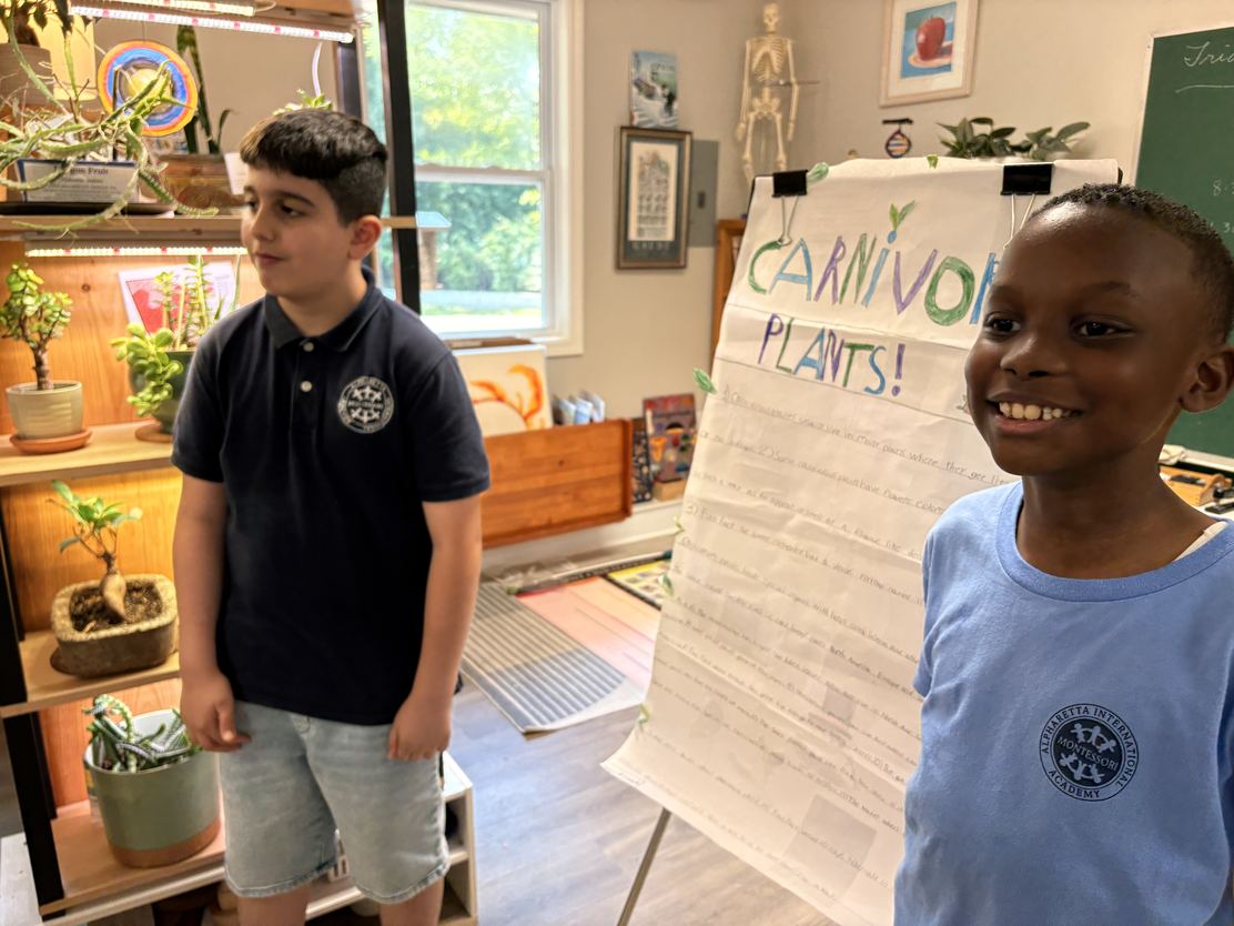 Two Elementary students presenting a hand-lettered poster titled Carnivorous Plants