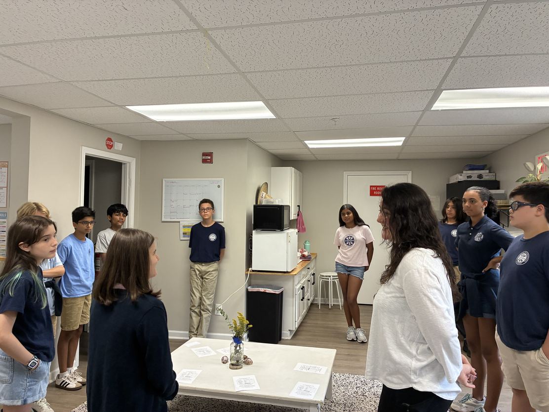 Middle School students standing in a circle with Ms. Ramirez during a classroom conversation