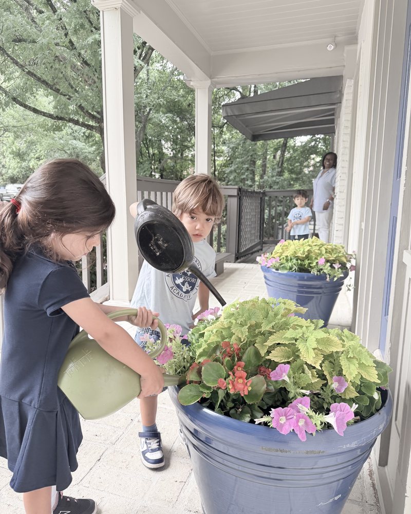 Children watering flowers in planters on the porch
