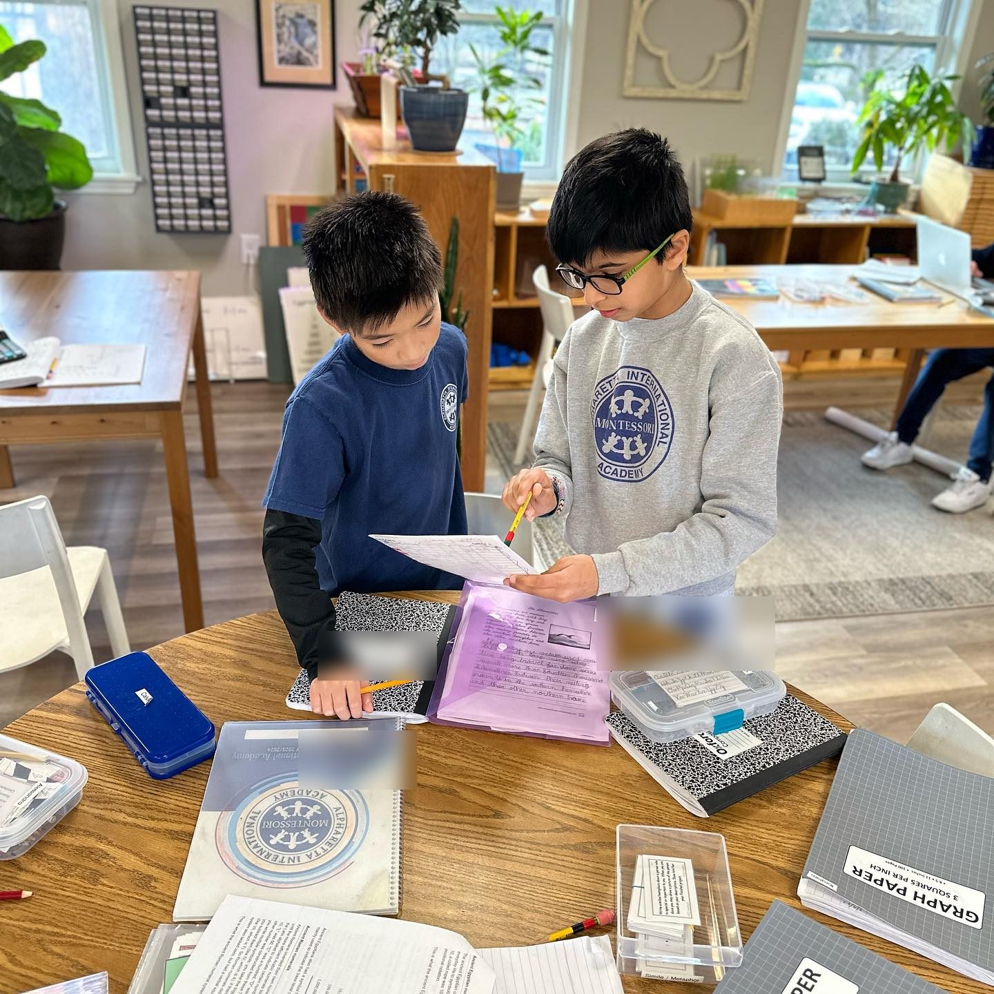 Two AIA Elementary students working through a project together at a classroom table