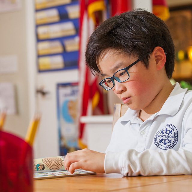 An Elementary student reading closely at his desk