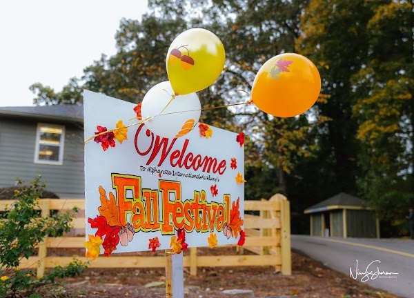 Welcome to AIA's Fall Festival sign with balloons at the campus entrance
