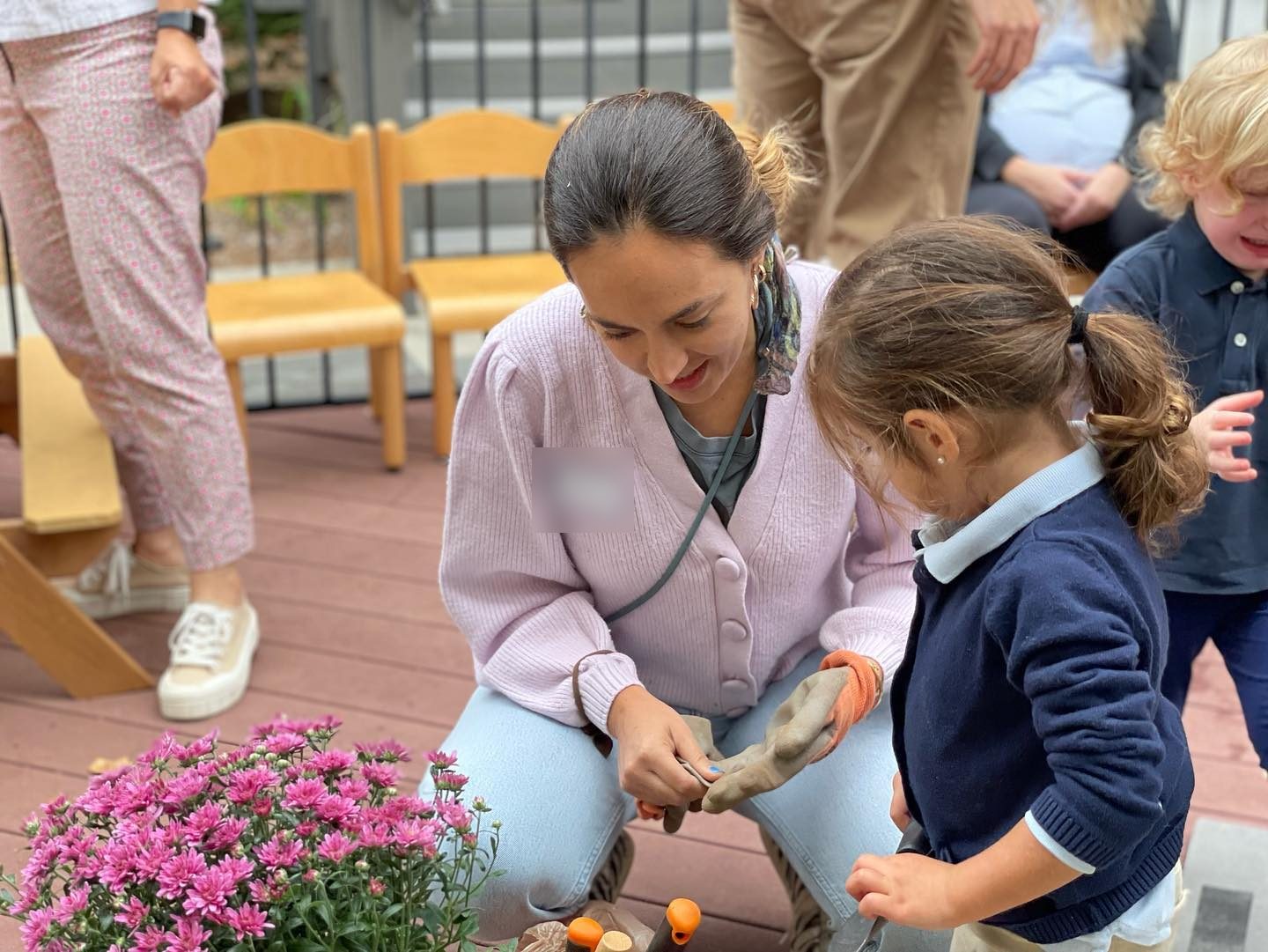 A parent volunteer planting flowers with a young student at an AIA family event