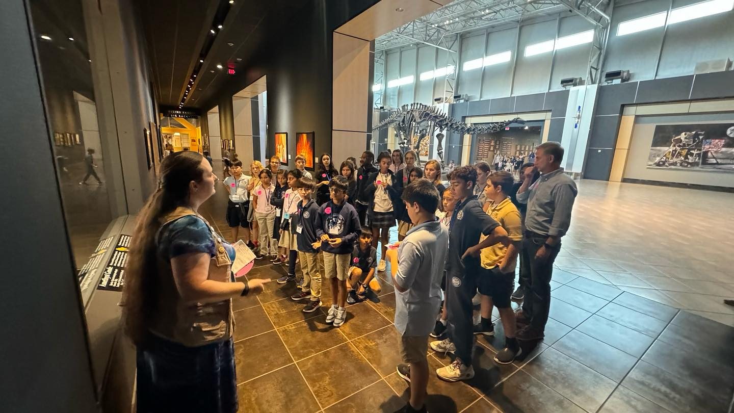 AIA students on a field trip at a natural history museum, gathered with their guide