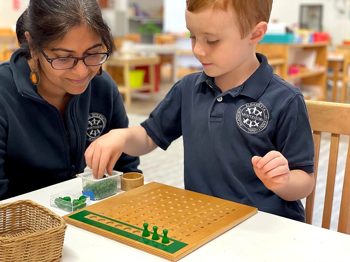 An AIA Montessori guide working one-on-one with a student at the multiplication bead board