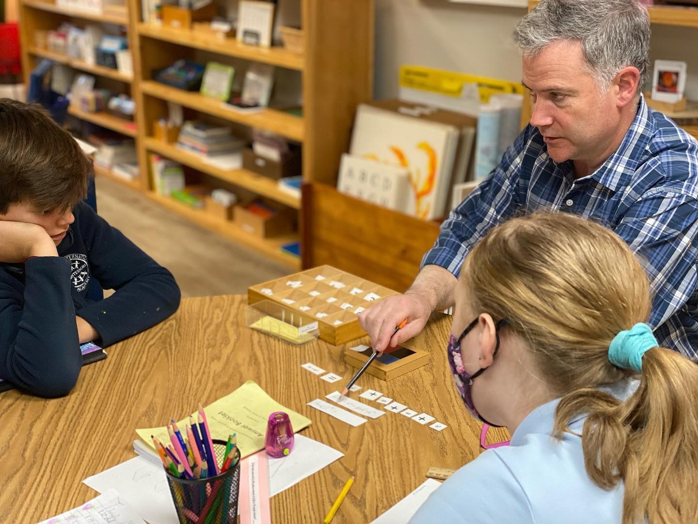 An AIA guide giving a math lesson with the stamp game to two Elementary students