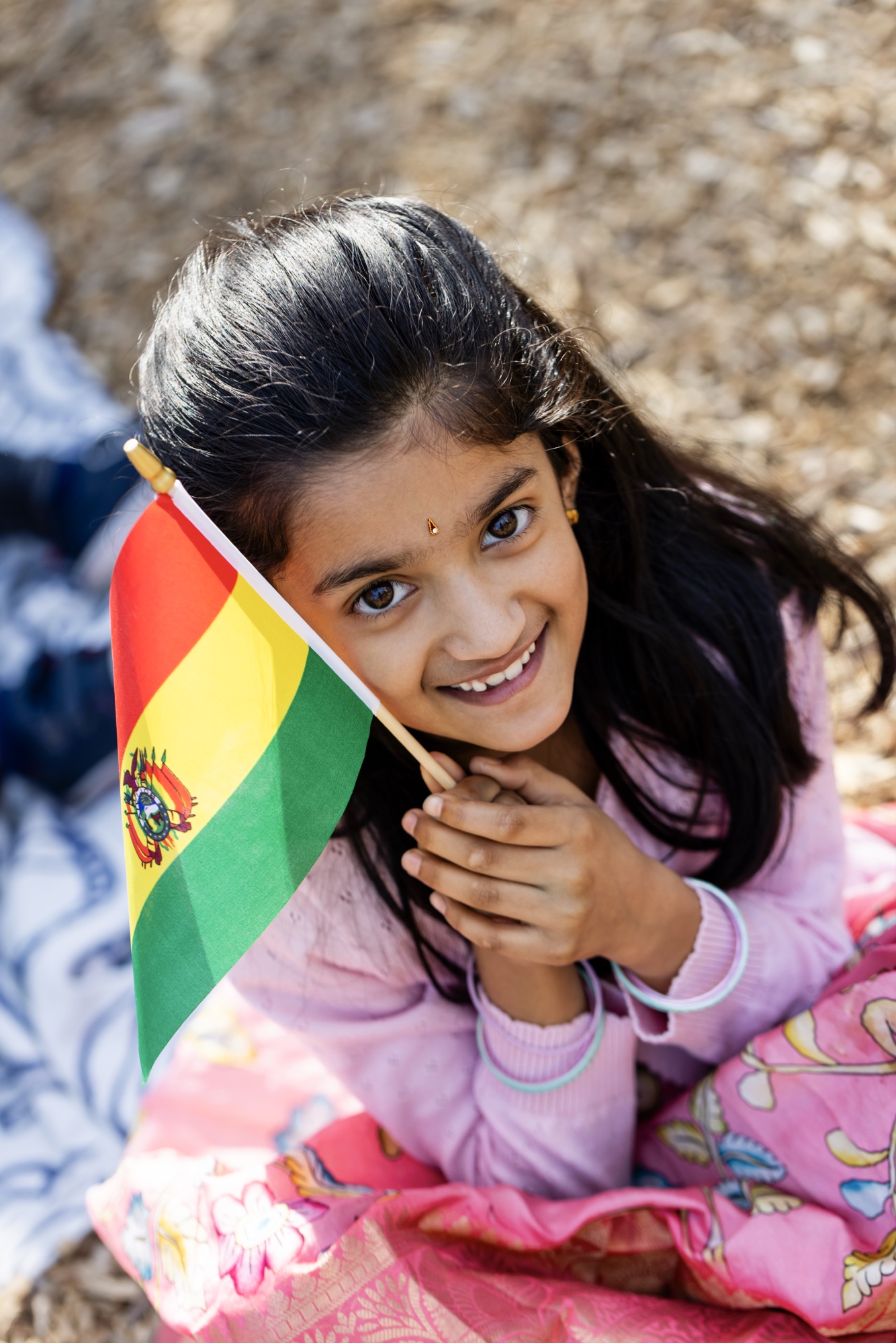 A student in traditional dress holding a Bolivia flag at AIA's International Day Festival