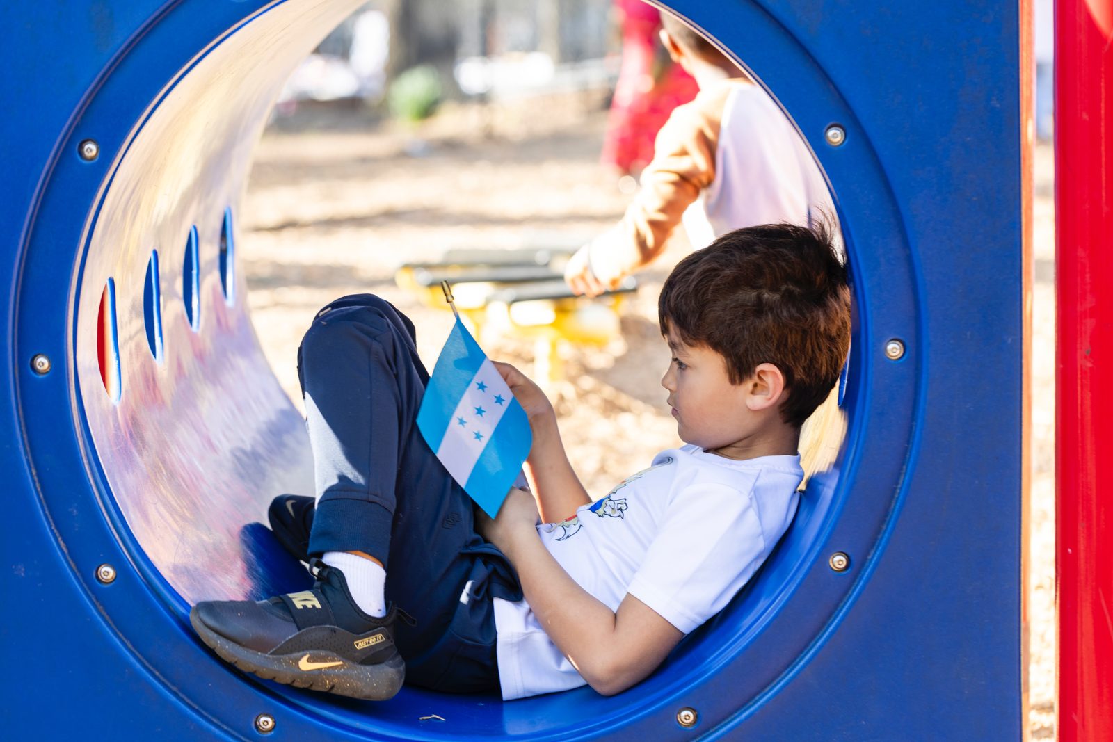 A child holding the flag of Honduras on the playground