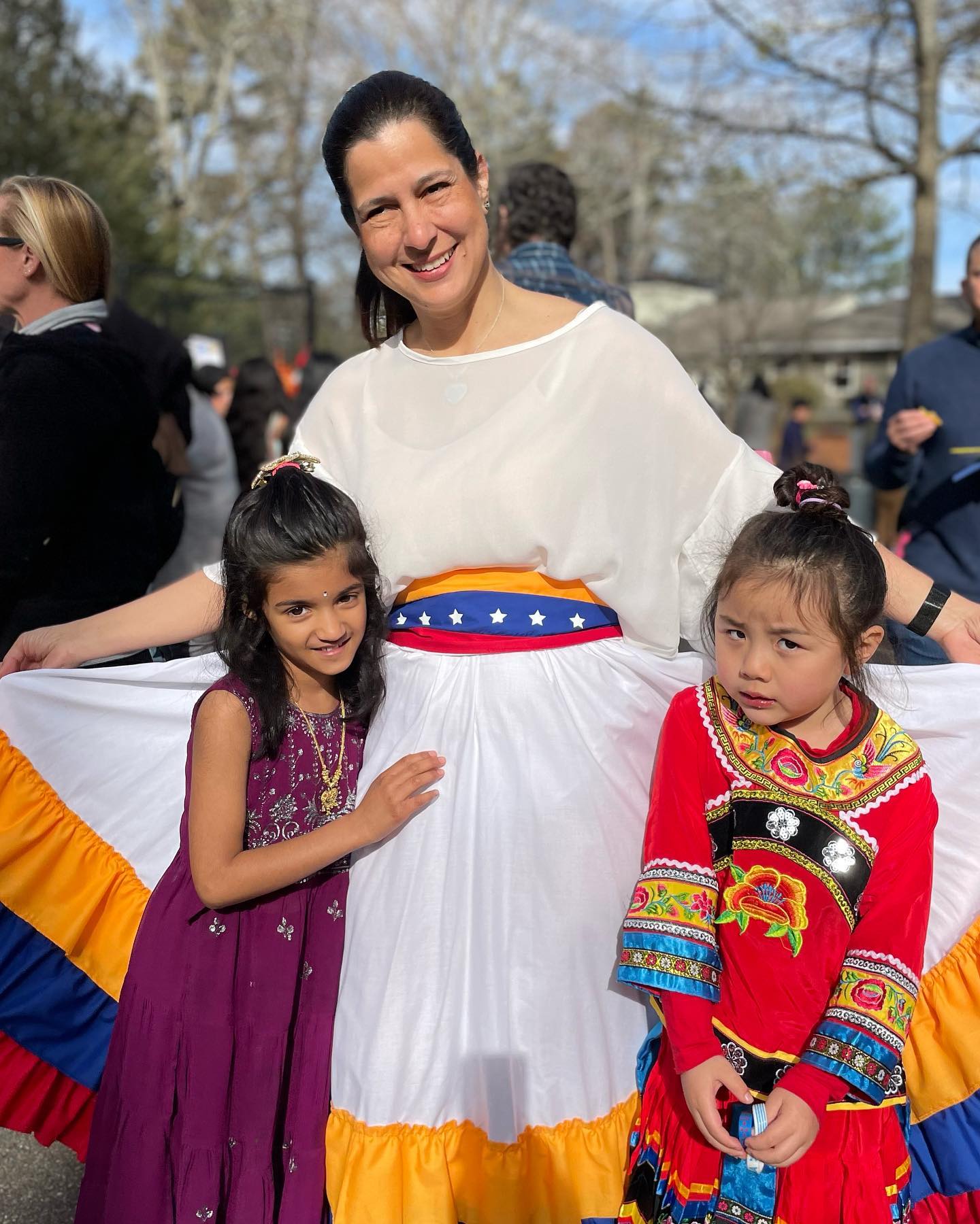 An AIA Spanish teacher in traditional dress with two students at International Day