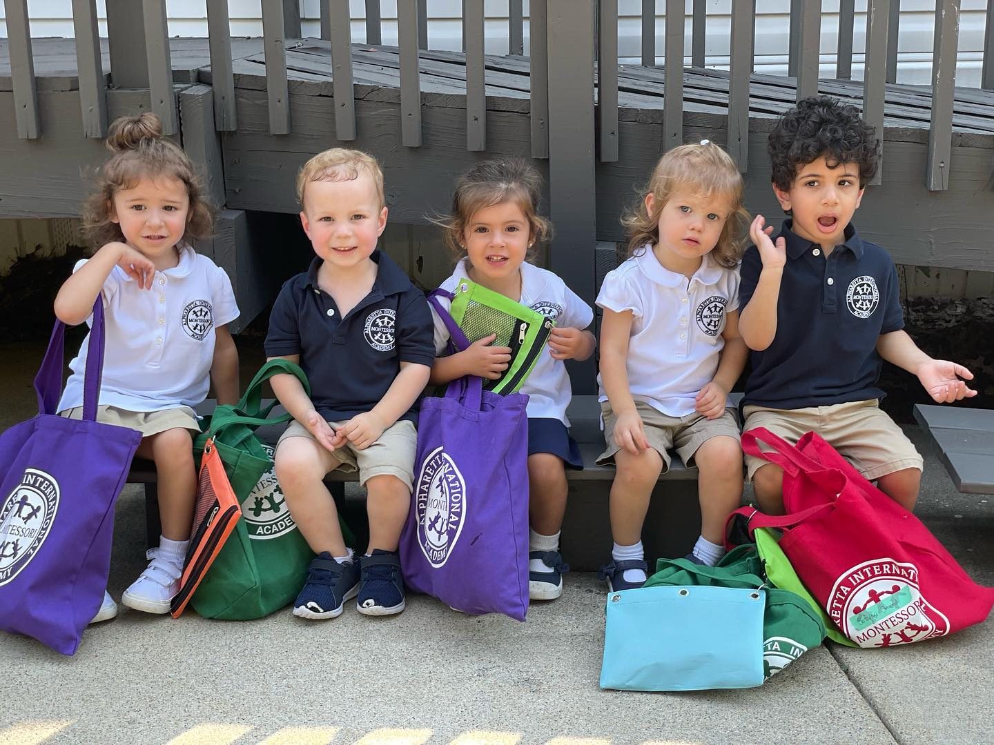 Five AIA Pre-Primary students on a bench with their school tote bags
