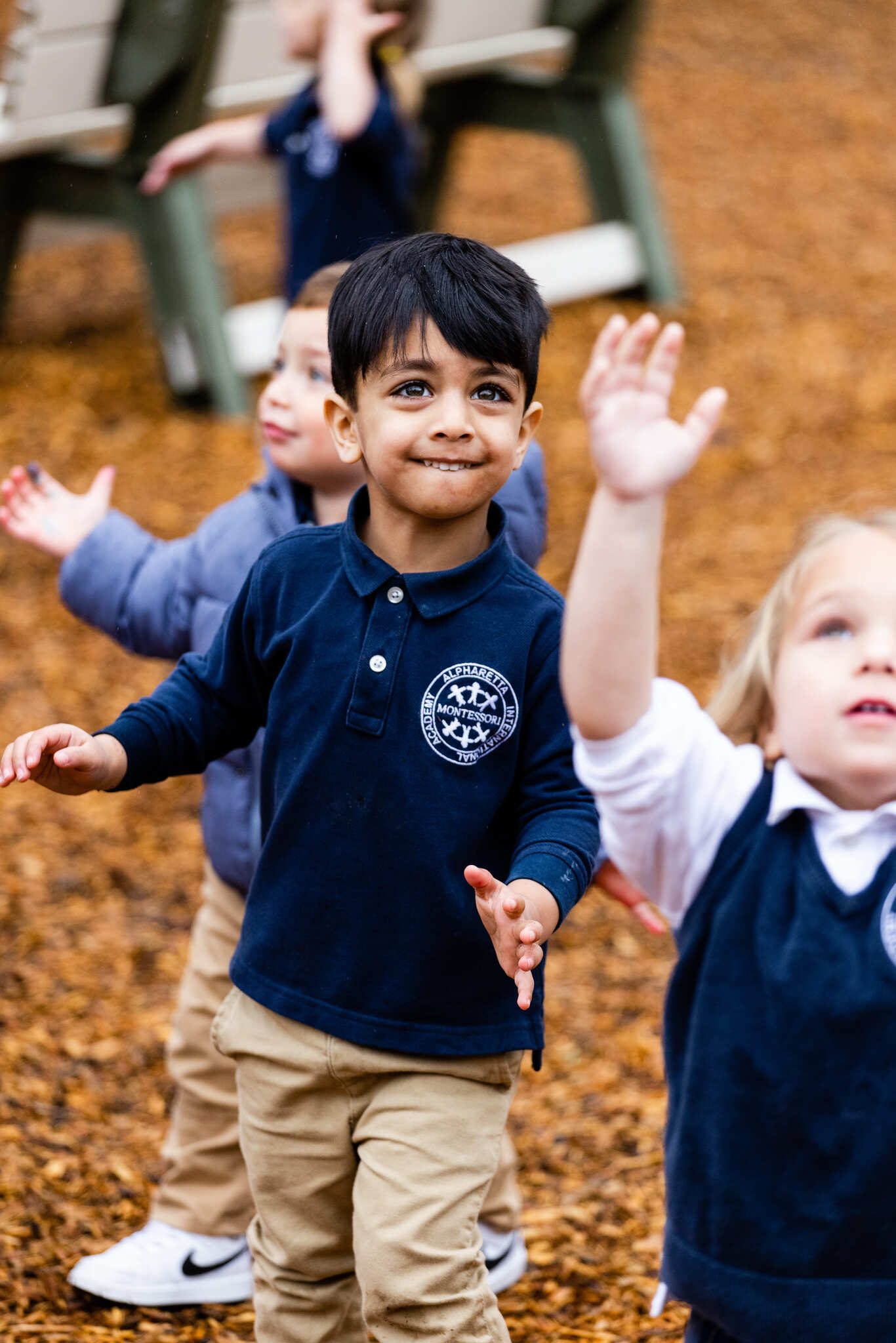 Pre-Primary children outdoors with their hands in the air