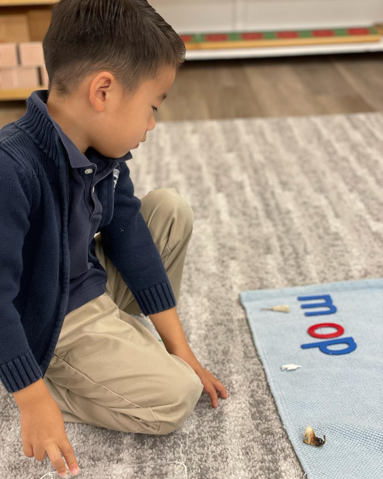 A Primary student building the word mop with the Montessori movable alphabet