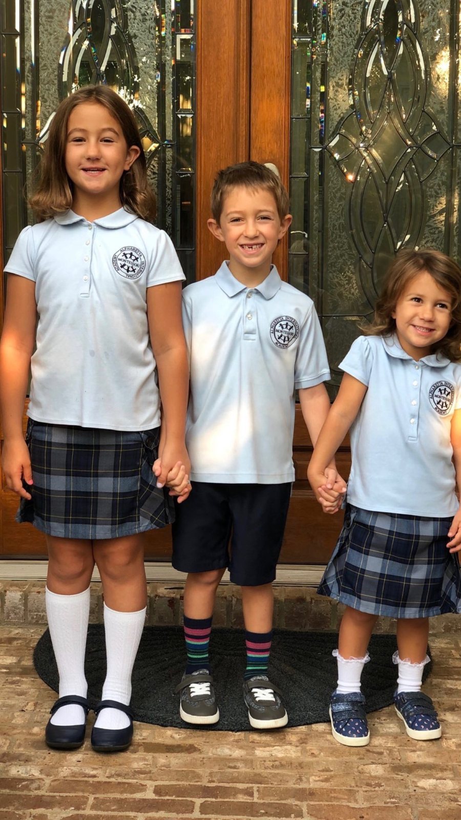 Three siblings in AIA uniforms holding hands, spanning Pre-Primary through Elementary