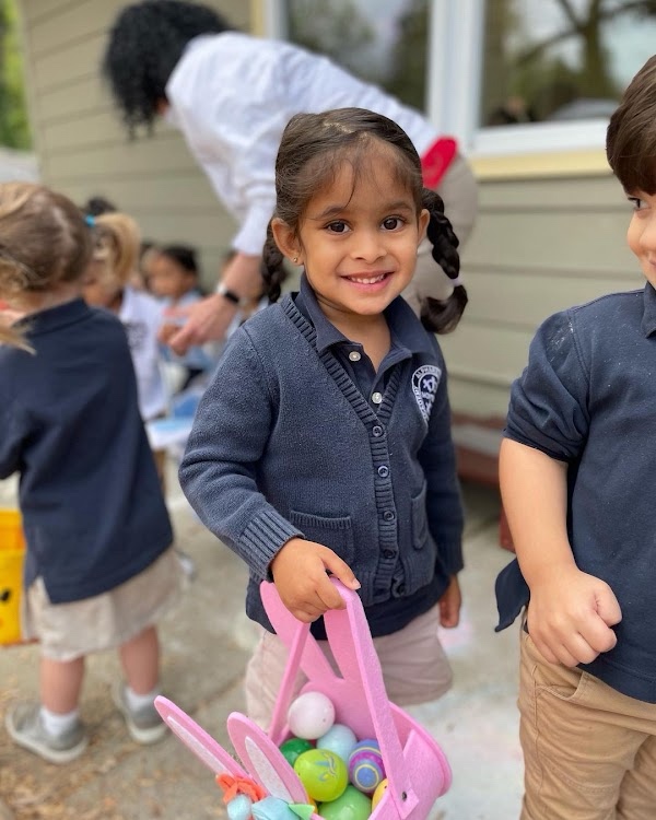 An AIA student holding an Easter basket full of colorful eggs during a spring celebration
