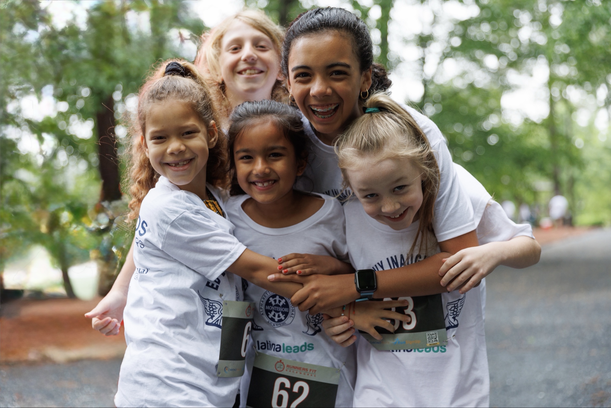 Students in race bibs with their arms around each other after the AIA 5K